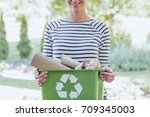 Aware woman separating paper from other waste, putting it into green container to save natural resources
