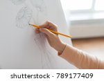 art, creativity and people concept - artist hands with graphite pencil drawing still life picture of flower in vase on paper at studio