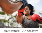 African curvy woman and personal trainer doing boxing workout session outdoor - Focus on her face