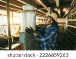 Small photo of Young african farmer woman holding milk churn inside cowshed - Focus on face