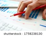 Small photo of Hand with red pencil lies on comparative chart. Build individual charts or view lead summary data. Dig deep into numbers and work with them manually. Comparative characteristics several companies