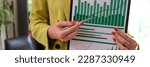 Small photo of Close-up of woman accountant showing financial report,pointing at statistics data. Paperwork, chart and graph. Marketing analytics and business stats concept