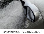 Closeup of a snow-covered car side mirror