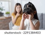 Small photo of Asian angry mother scold her stubborn daughter while her daughter crying.