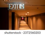 Small photo of Emergency exit sign at the corridor in building. Green fire exit sign hanging on ceiling on dark corridor in building near fire emergency exit door. Green emergency exit sign.