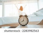 Young woman at home in morning, focus on alarm clock, alarm clock wake up woman in the room