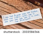Small photo of Closeup of handwritten message on wooden background with closed Bible. God Jesus Christ is the I AM, Alpha and Omega, First and Last, the LORD Almighty. Revelation biblical concept.