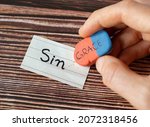 Small photo of A handwritten word sin with a hand holding a rubber eraser with grace text on wooden background. Christian biblical concept of grace, mercy, sacrifice, and sacrifice of God Jesus Christ. A close-up.