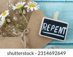 Small photo of Repent, handwritten word with flowers and vintage paper envelope on wooden table. Top view. Christian repentance, confession of sin, obedience to God Jesus Christ. Biblical concept.
