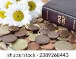Small photo of Coins, flowers, and holy bible book on rustic table. Close-up. Selective focus. Christian tithe, offering, generosity, and church contribution concept.