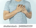 Small photo of asian man pressing chest with painful expression. Severe heartache, having a heart attack or painful cramps, heart disease.