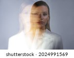 Small photo of young stylish woman in a white jacket, distortions of the model's face on a long exposure. Second personality, alter ego concept