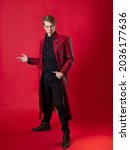 Small photo of An outrageous young man in a daring red coat in a vintage noir style, photo on a red background
