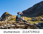 Small photo of A young man with a backpack looks around enjoying the mountain landscape, untouched nature. Mountain travel, local tourism