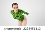 Small photo of Stylish bright dancer in a bright green leopard print bodysuit, studio photo on a white background. Plastic body, pretentious pose