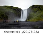 Tourists gazing upon the popular destination of Skógafoss in Iceland. 

This icelandic waterfall is a busy tourist destination on Route 1.

Long exposure photograph.