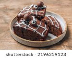 Chocolate cobweb brownies with candy spiders, homemade treats for Halloween on rustic wooden background