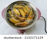 Small photo of Yellow ripe bananas are in boiling water in a red electric boiler