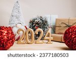 Background for greetings with empty space. Happy new year card. Figures 2024 on a light wooden background with Christmas toys. Front view