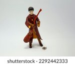 Small photo of Harry Potter dressed in Hogwarts school uniform of quidditch game. Collectible toy for children. Character from the J. K. Rowling. Broom. Golden snitch ball. Front view.