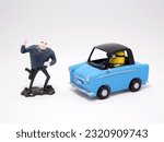 Small photo of Minion and Gru. Villain Gru. Minion driving a car. Characters from the famous Despicable Me movies. Kinder Egg Toys. Toy car.