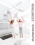 Small photo of Evening time for fun. Sleepover party ideas. Sisters play pillows bedroom party. Pillow fight pajama party. Girls happy best friends or siblings in cute stylish pajamas with pillows sleepover party.