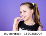 Small photo of Girl smiling face holds sweet marshmallows in hand violet background. Sweet tooth concept. Kid girl with long hair likes sweets and treats. Calorie and diet. Incorrigible sweet tooth. Hungry kid.