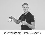 Small photo of He is always punctual. Punctual man hold alarm clock showing thumbs up. Happy being on time. Precise time. Punctuality and accurate timekeeping. Regular as clockwork