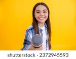Small photo of teen girl singer interviewing in studio. young girl singer perform karaoke isolated on yellow background. With microphone in hand teenage girl singer. young karaoke singer girl hold microphone