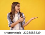 Small photo of amazed teen girl presenting product to the camera. teen girl presenting product to customers. teen girl presenting product to audience. teen girl presenting her new product on studio background