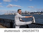 Small photo of Sportsman stretch to improve flexibility. Sport man stretching and warm up for workout. Stretching routine of sportsman outdoor in NY. Sportsman stretching his muscles after running. Stretch sequence