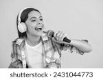 Small photo of happy teenage singer girl singing music on background. singer girl with microphone in music studio. talented music singer girl in headphones. girl singing into music microphone isolated on yellow