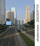 Small photo of JAKARTA - Indonesia. July 06, 2021: Emergency public activity restrictions (PPKM Darurat) call forth a quiet traffic on Sudirman road, the restrictions aim to curb a severe wave of COVID-19.