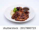 Tasty grilled ckicken chop served on a white plate with sides rice and black pepper sauce - white background