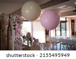 large gray and pink helium balloons with bows hanging in a celebration room next to a sweet table