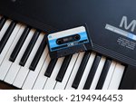 Small photo of Vintage audio tape cassette on a synthesizer keys from above,Retro cassette.Audio equipment for analog music records. Black stereo tape. Isolated plastic musical device. Old-fashioned mixtape of tunes