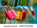 A padlock, a key lock with heart-shaped love signs, is being locked into a bridge rail.