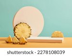 Small photo of Front view of fresh pineapple slices and white empty podium on pastel blue background. Minimal art background with blank platform for display cosmetics and product of pineapple extract.