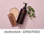 Small photo of A amber pump bottle with comb, petri dish filled liquid and lantana camara on pink background. Mockup for shampoo of natural extract. Tropical herbal ingredients good for strong and smooth hair