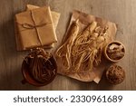 Small photo of Dang shen inside a bowl, Ginseng placed on a paper arranged with other traditional herbs and several medicine packs. Herbs help the body to get more energy