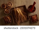 Small photo of Wooden tray in square-shaped containing Ginseng and Red ginseng. Three bowls of other herbs are displayed. Herbs are used to prevent or treat health problems