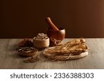 On the wooden table, ginseng root and medicinal herbs displayed on wooden tray with wooden mortar and pestle. Scene for medicine advertising, photography traditional medicine content