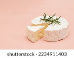 Delicious fresh italian Camembert cheese. Fresh Camembert cheese with rosemary on pink background. Top cheese of Italy - Camembert. Italian camembert cheese side view.
