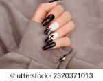 Halloween nail design black white color with cross. Female hand with autumn manicure, top view. Halloween concept