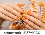 Female hand with orange nail design. Glitter orange nail polish manicure. Female model hand with perfect manicure.
