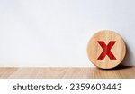 Small photo of Circle wooden block with red wrong mark. Illustrate the wrong login decision concept. Vote and think wrong. Choose a business for difficult situations, true and false symbols. Choose the wrong sign