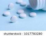 White round pills and pill bottle on blue background