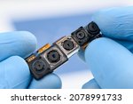 Camera modules with different sensor technology and resolution in scientist hands. Smartphone cell phone cameras research or repair concept in laboratory.