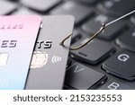 Small photo of Credit card on fishing hook pulled from stack on keyboard, phishing scam data theft concept