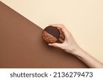 Small photo of Woman's hand with whoopie pie dessert on beige background